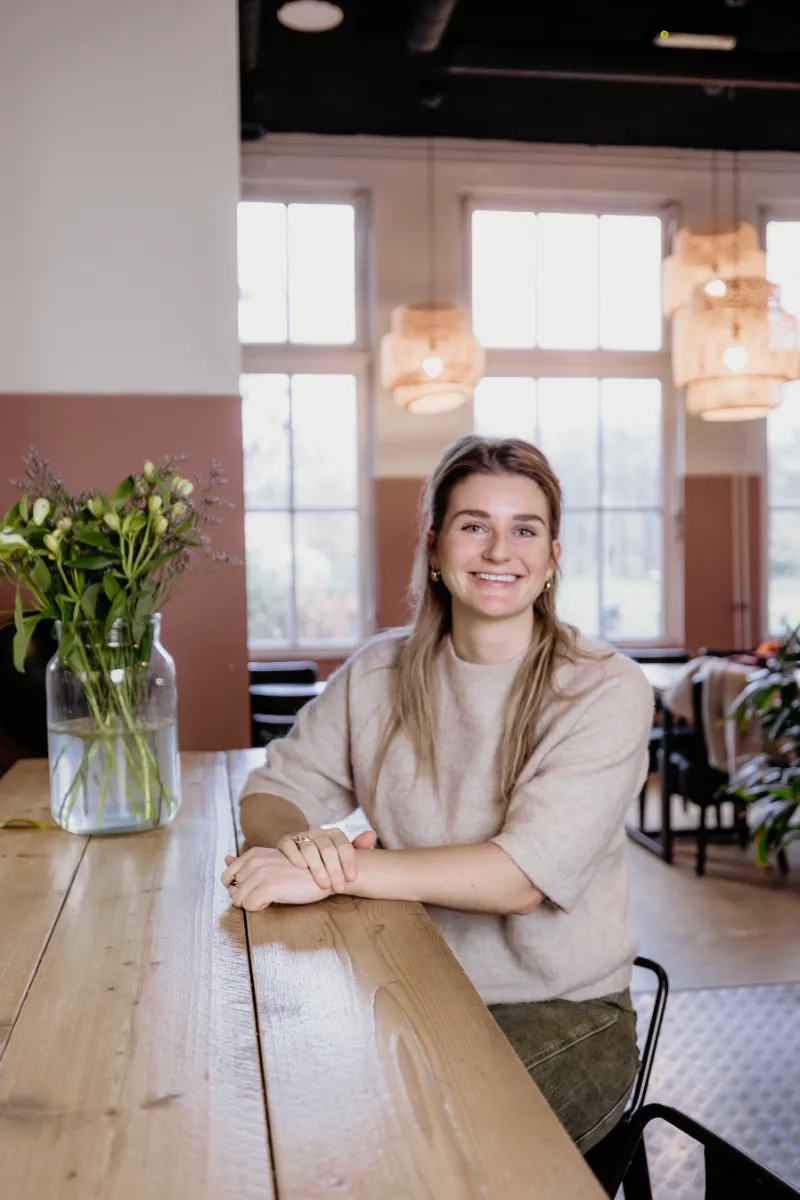 Eline zittend aan een tafel
